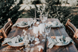 Houten barnwood tafel met borden, vintage glazen en groene servetten door Elle Weddings