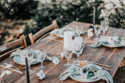 Houten barnwood tafel met borden, vintage glazen en groene servetten door Elle Weddings